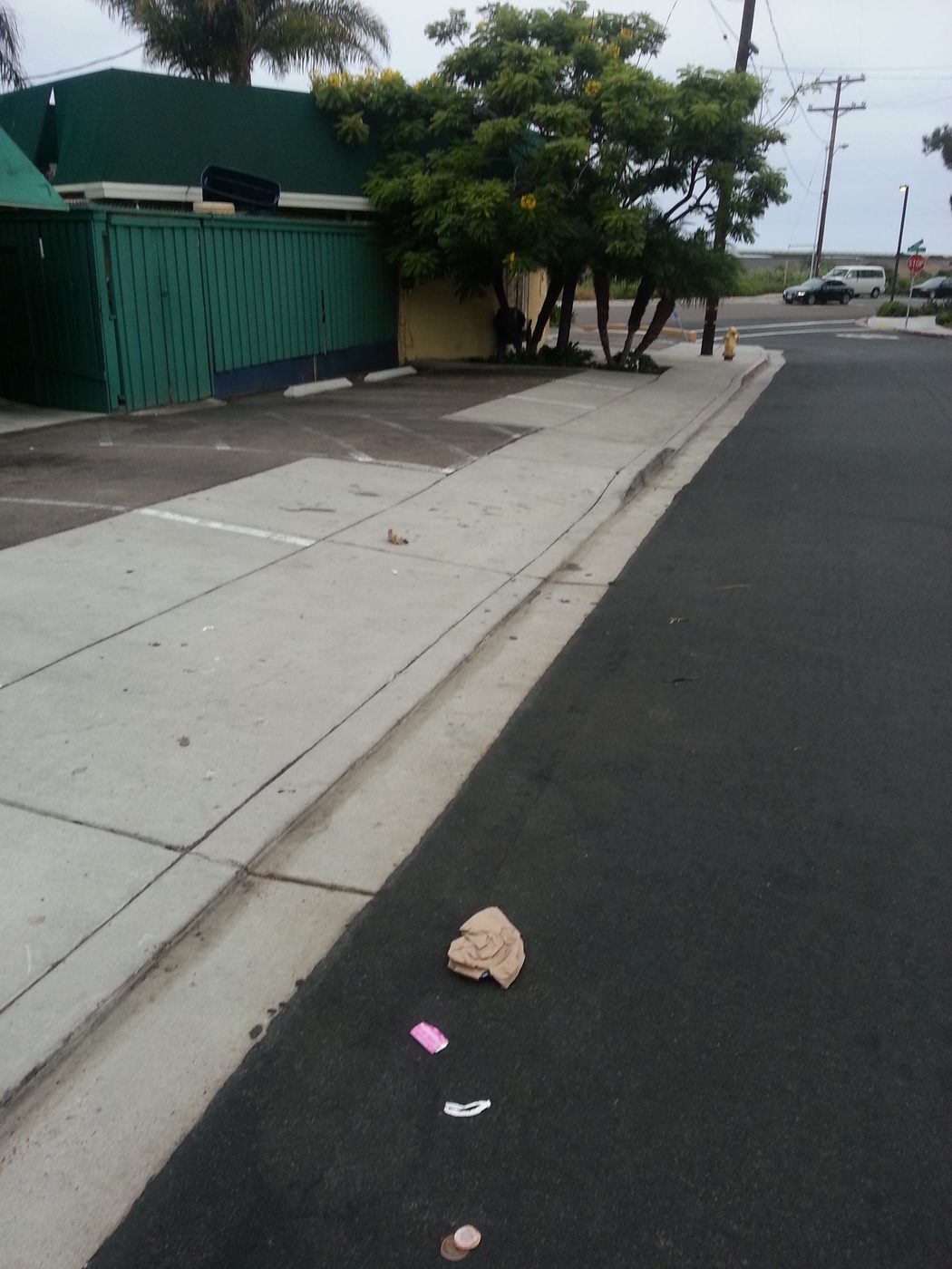 Wrappers and a cup sit in the street where we live.