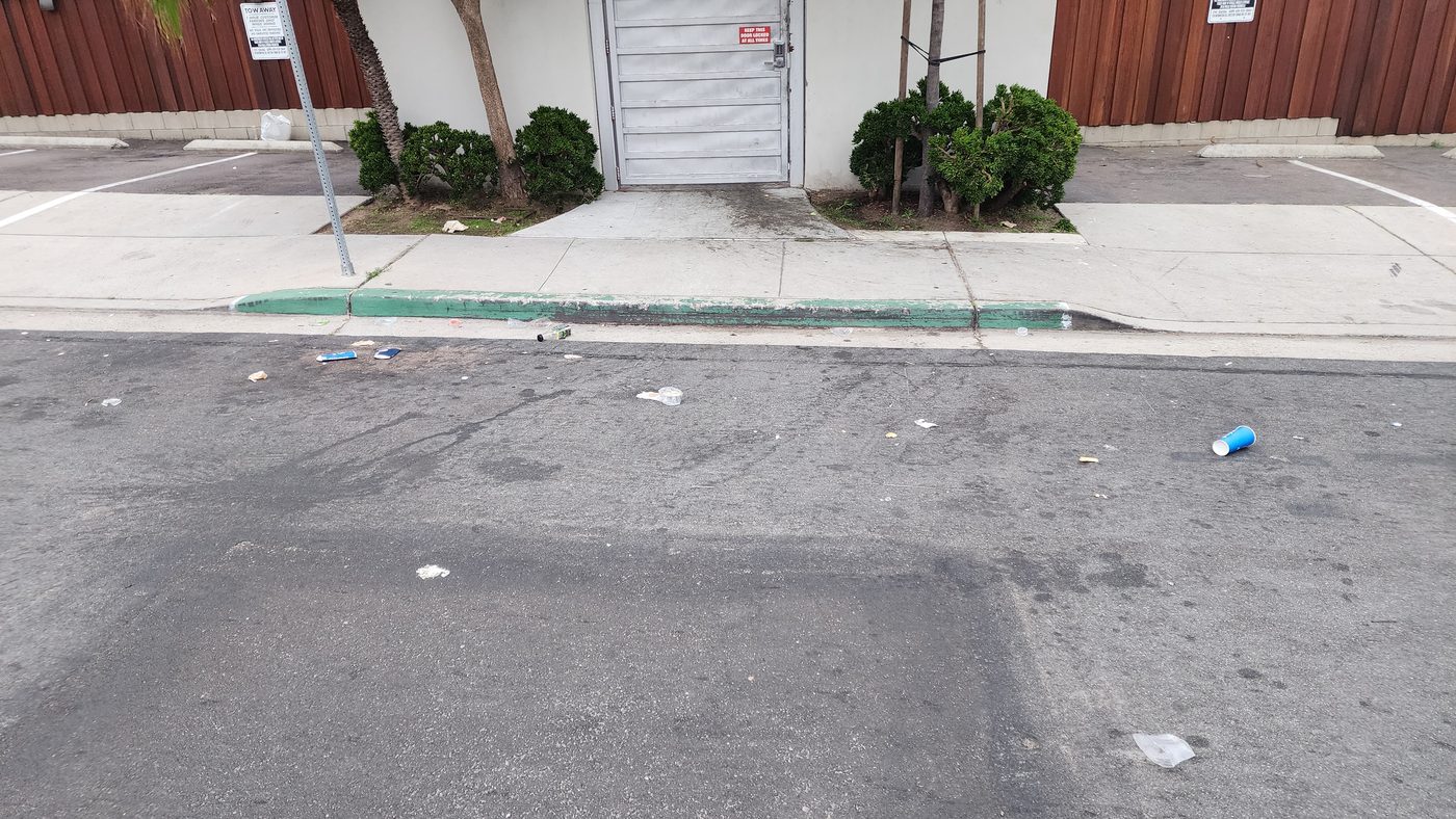 Cups and debris pile up in the gutter outside the complex's service door.